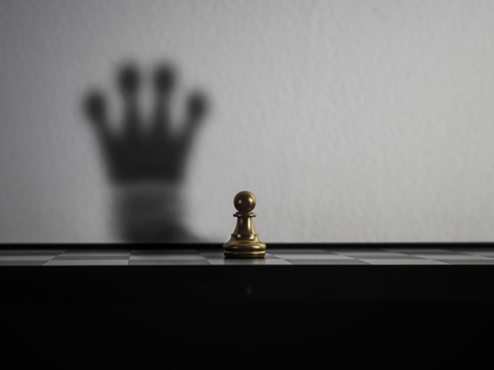 L'immagine di un pedone degli scacchi la cui ombra proiettata sul muro corrisponde al pezzo della Regina