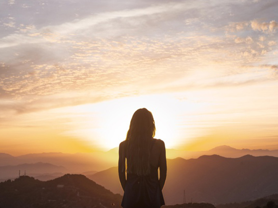 immagine di una donna serena al tramonto medita domada: la mindfulness funziona